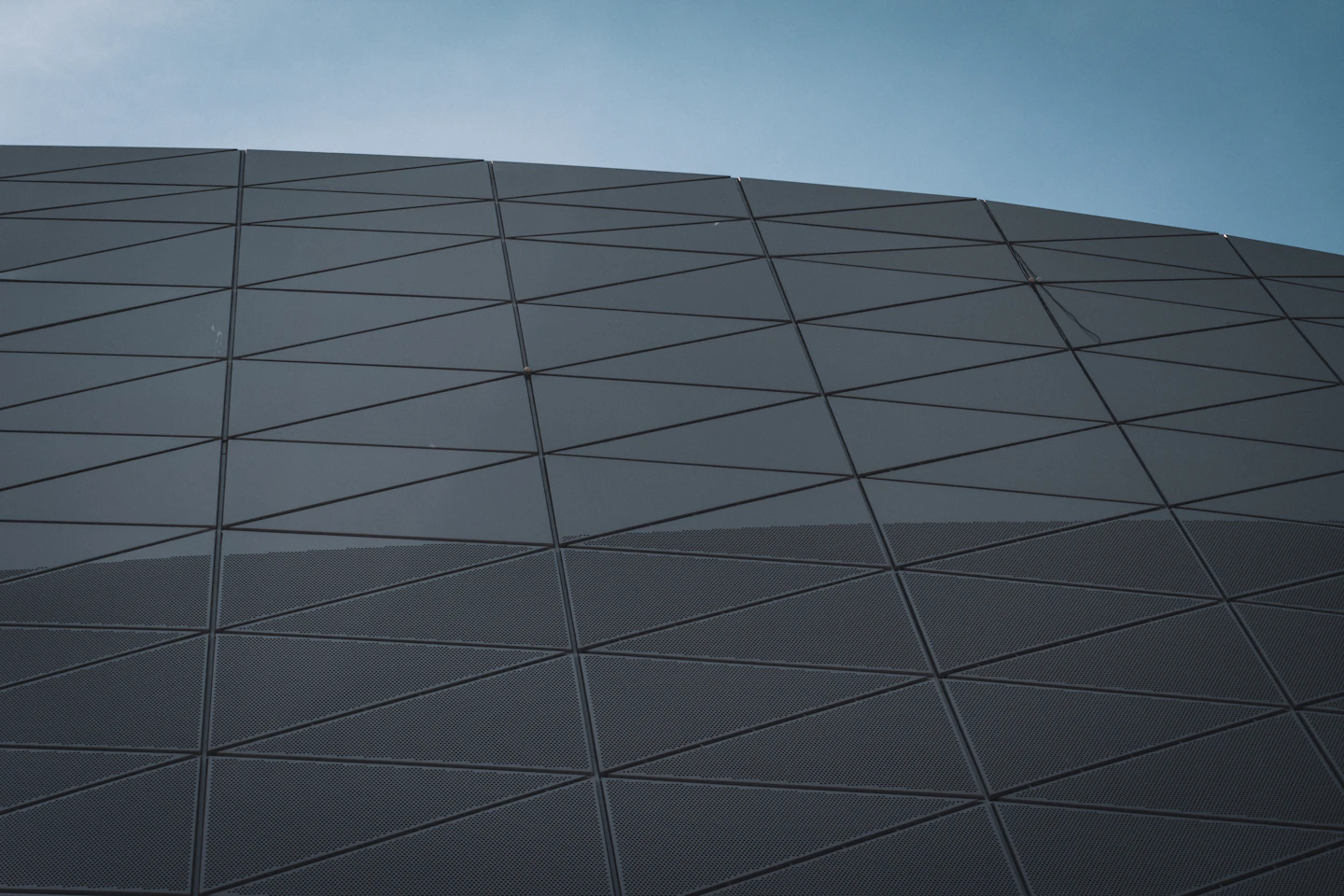 Façade moderne composée de panneaux géométriques aux lignes structurées.
